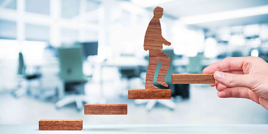 Wooden parts symbolize steps on which a wooden figure steps upwards.