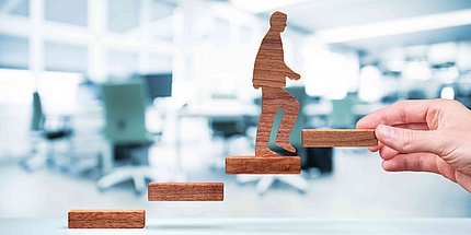 Wooden parts symbolize steps on which a wooden figure steps upwards.